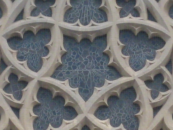 Decorative stone lattice work with interwoven foliage patterns on a building facade.
