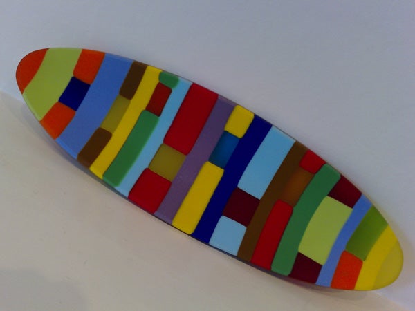 A colorful patterned surfboard-shaped object on a white surface.