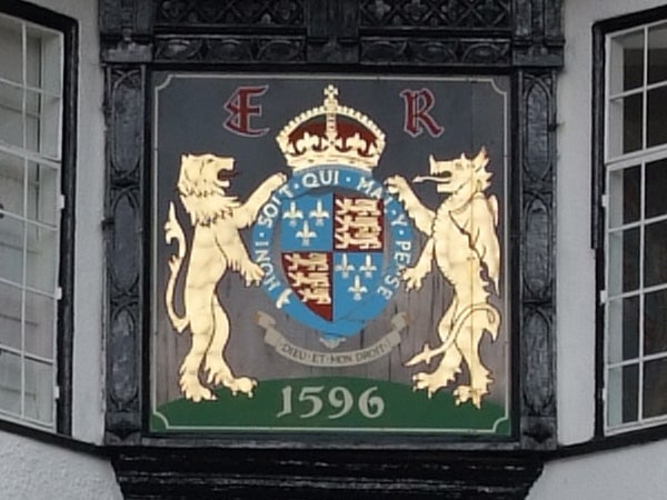 Coat of arms with a shield flanked by two lions under a royal crown and the initials E R, displayed on a building facade with a date of 1596.