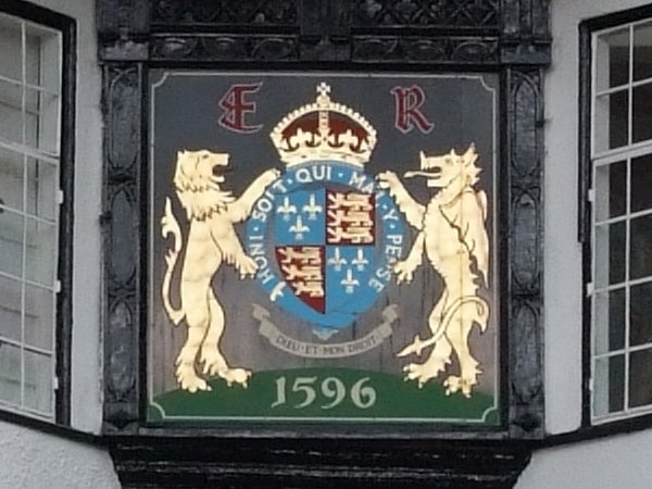 Coat of arms displayed on a building façade featuring two lions and a shield with a crown and initials 