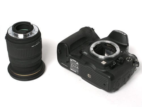 Fujifilm S5 Pro DSLR camera body without lens next to a detached camera lens on a white background.