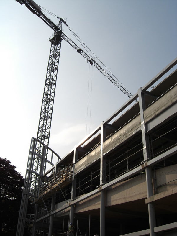 The image appears to show a construction site with a tall crane and a multi-story building under construction with visible scaffolding and incomplete structural elements. It's taken during the day under clear skies. However, the image provided does not directly relate to the Casio Exilim EX-Z1050, nor does it depict the product, a view from the product's perspective, or a performance graph for the product.