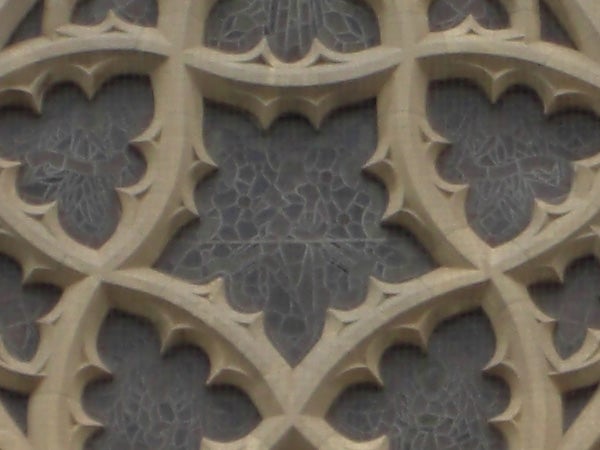 The image provided appears to be an architectural detail featuring a close-up view of stone tracery with a gothic design, consisting of interlaced arch patterns and delicate foliage motifs.