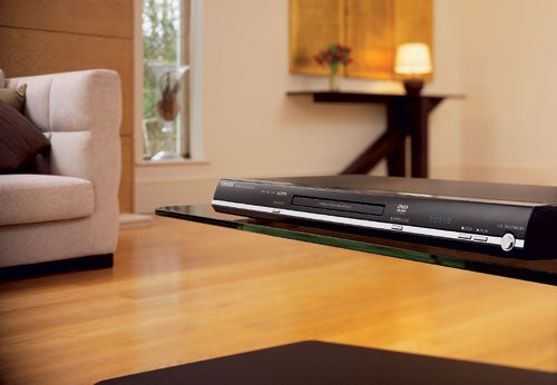 Toshiba SD-370E Upscaling DVD Player placed on a glass shelf with a modern living room in the background