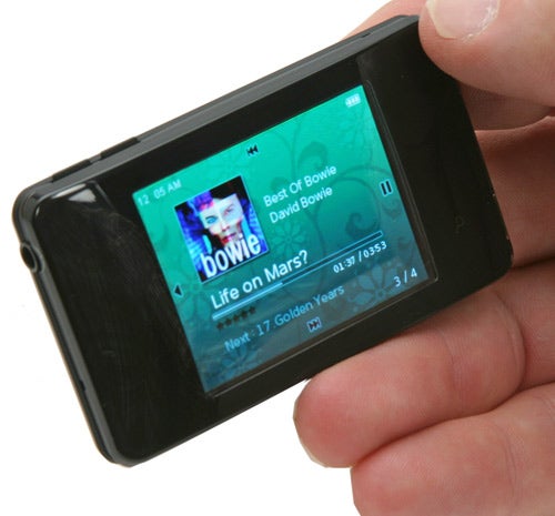 A person holding an iRiver clix 2 4GB MP3/Media Player with the screen displaying David Bowie's 