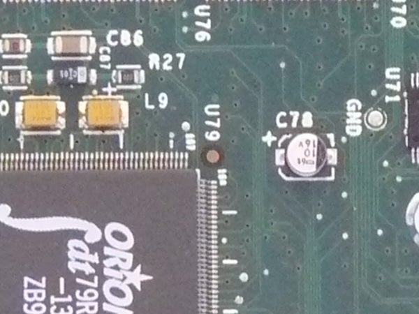 Close-up of an electronic circuit board with various components such as capacitors, resistors, and an integrated circuit labeled.