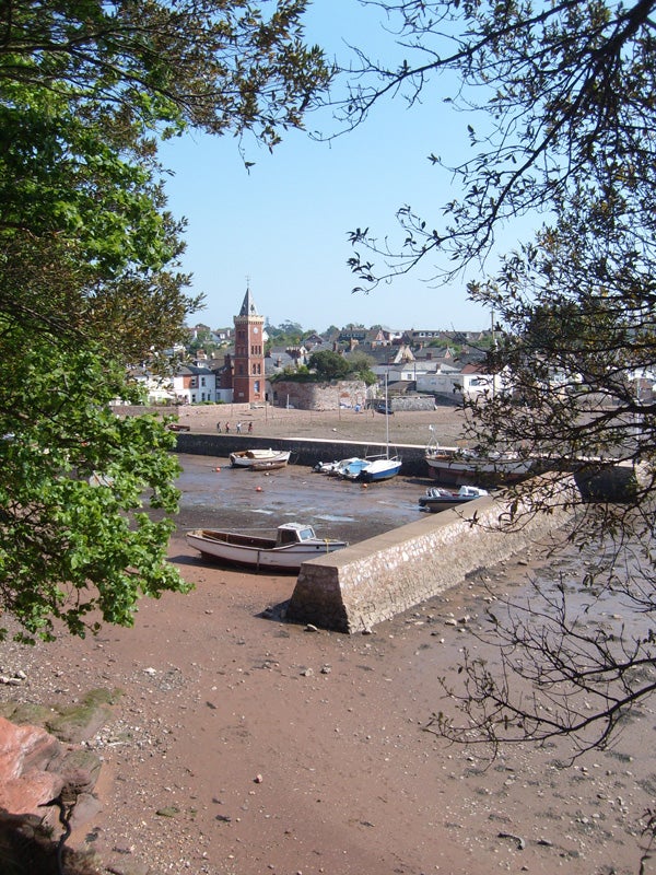 Boats on a river bank with a clock tower in the background.