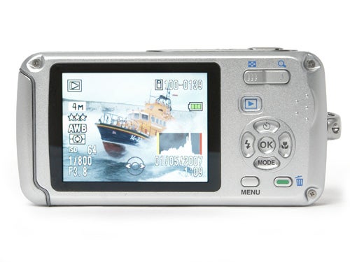 Pentax Optio W30 digital camera viewed from the back showing the LCD screen with a displayed photo of a ship at sea, alongside control buttons and a navigation pad.