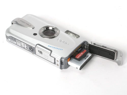 Pentax Optio W30 waterproof camera with open battery compartment showing battery and SD card slot.