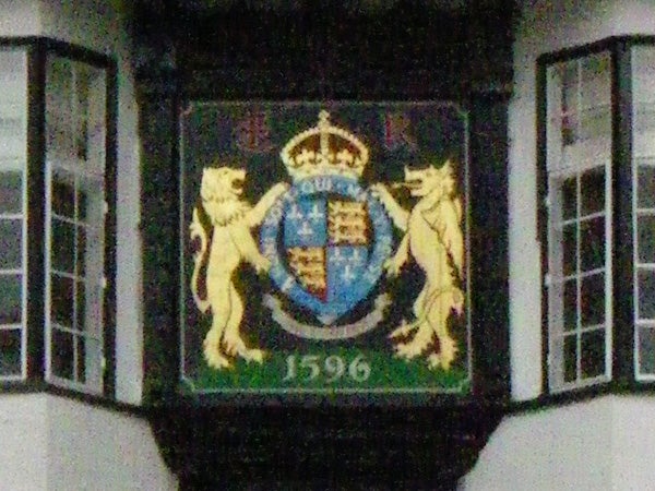 The image features a blurry photograph of an ornate coat of arms dated 1596, flanked by two lions standing on hind legs, displayed on a wall. The image may demonstrate the Pentax Optio W30's performance in low-light conditions or its limitations in capturing fine details at a distance.