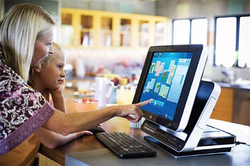 Woman and child using HP TouchSmart IQ770 PC in kitchen.