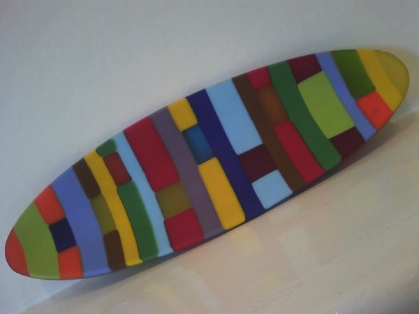 Colorful surfboard-shaped decorative object on white background.