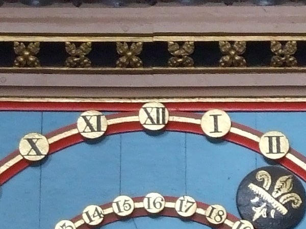 Close-up of a colorful, ornate clock face with Roman numerals.