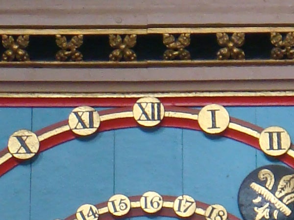 Clock with roman numerals on ornate building facade.