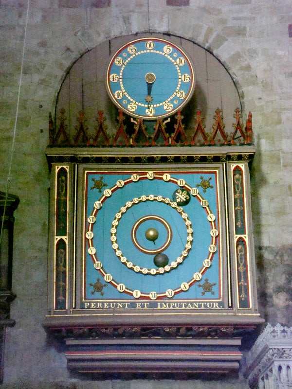 Ornate astronomical clock on an ancient stone wall.