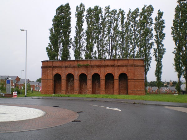 Red brick structure with arches and trees in the background.