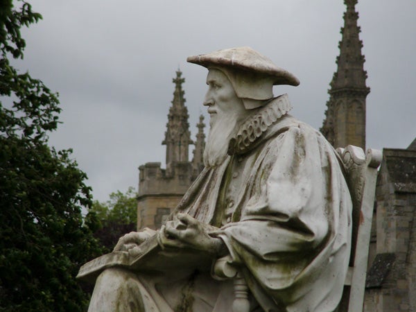 Statue of a historical figure with cloudy sky background.