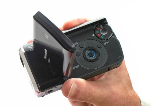 Hand holding Panasonic SDR-S10 Camcorder with flip screen.