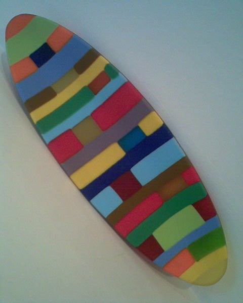 Colorful patterned surfboard against a white background.
