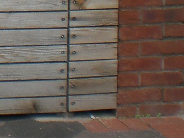 Blurred photo of wooden siding and brick wall.