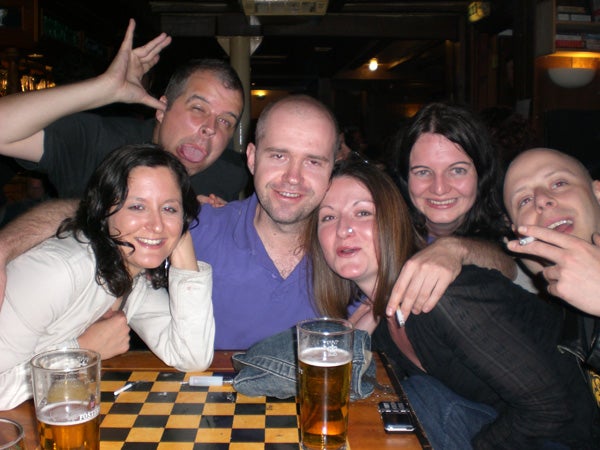 Group of people enjoying drinks around a checkered table.