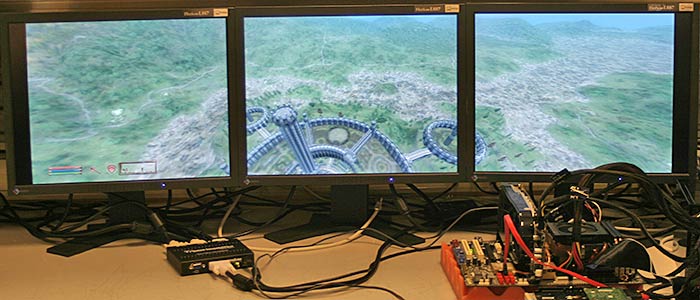 Matrox TripleHead2Go with three monitors showcasing panoramic game view.