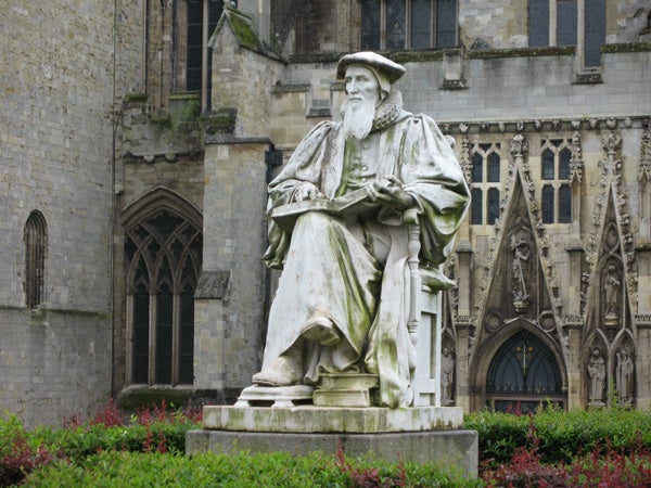 Statue in front of an old cathedral with greenery.