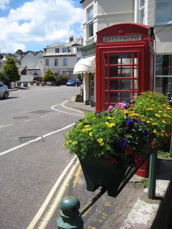 Red telephone booth and flower bed on a sunny street.