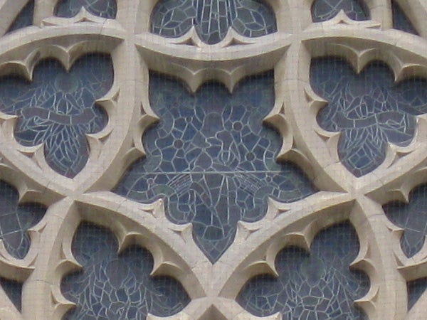 Gothic architectural stone window detailing with cracks.