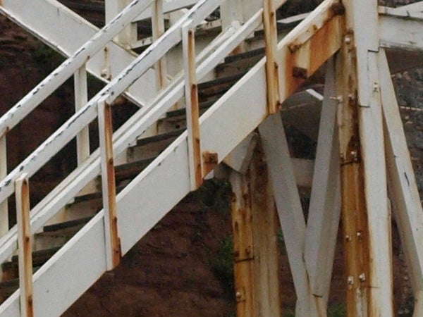 Close-up of rusty metal staircase with white railings.