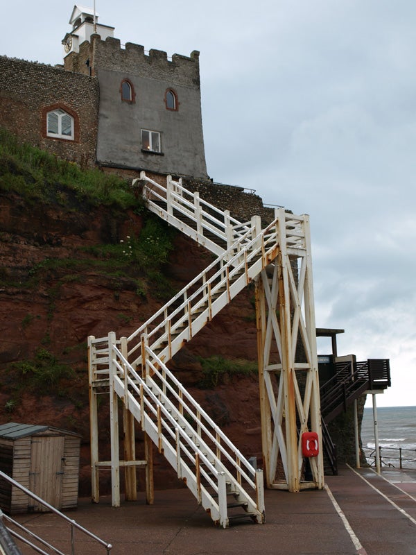 Wooden staircase leading to a castle on a cliffside.
