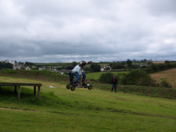 Person riding a mountain board on a grassy hill