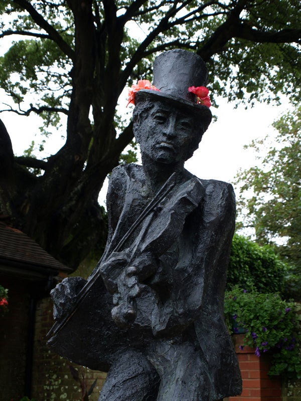 Statue of a figure with a top hat adorned with flowers