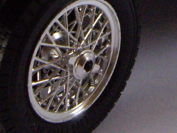 Close-up of a classic car wheel with wire spokes.