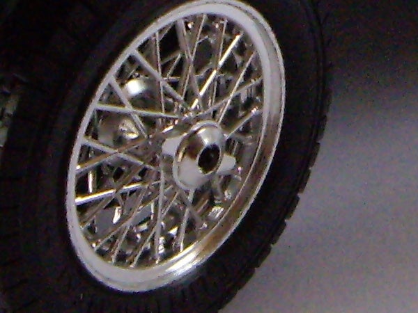 Close-up of a wire-spoke wheel on a dark background.