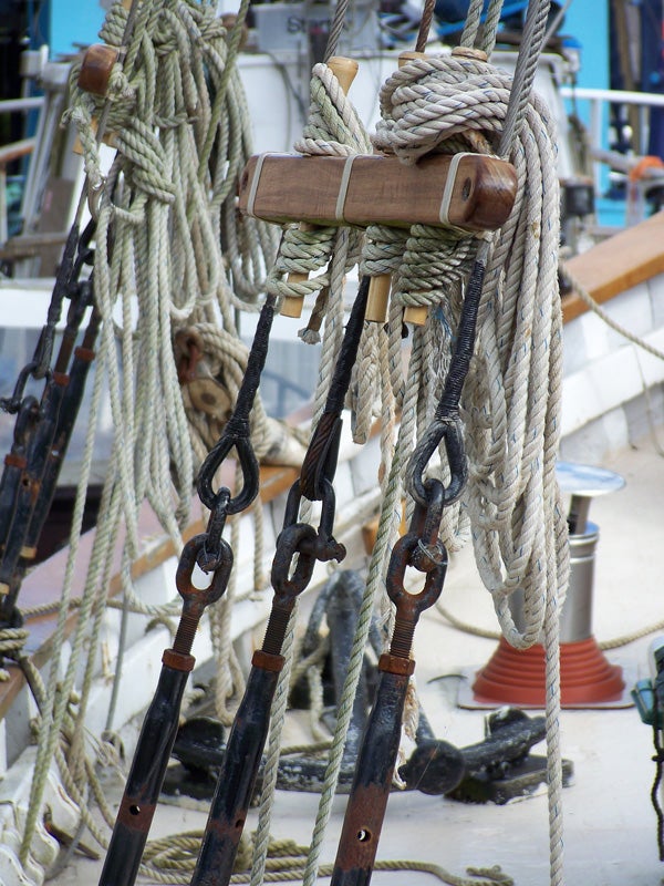 Close-up of ship's rigging with ropes and wooden pulleys.