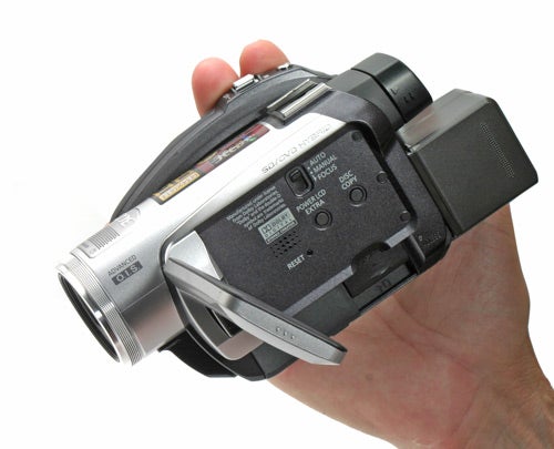 Hand holding a Panasonic HDC-SX5 camcorder.
