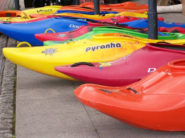 Colorful kayaks lined up on pavement.