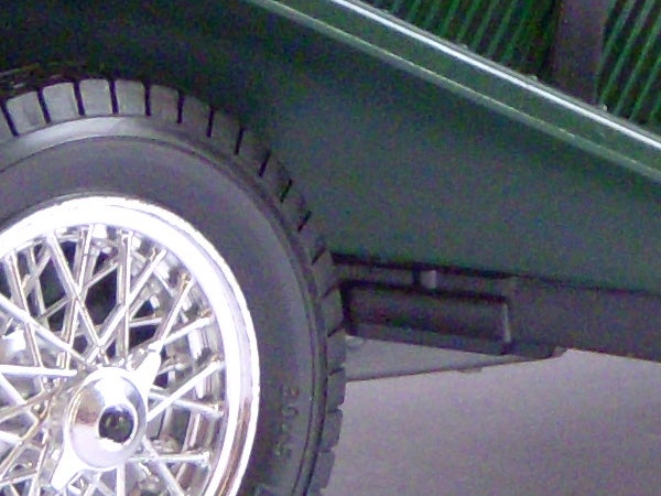 Close-up of a vehicle's wheel and part of green bodywork.