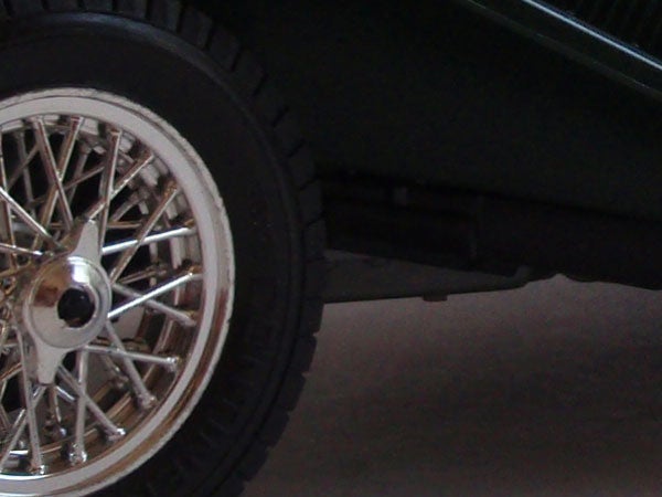 Car wheel and part of the fender against a grey background.