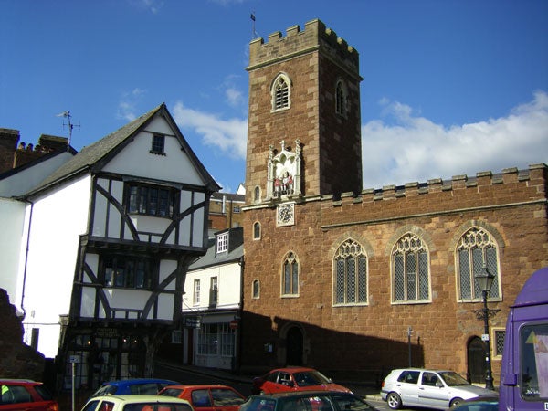 Old brick church and half-timbered building under blue sky.