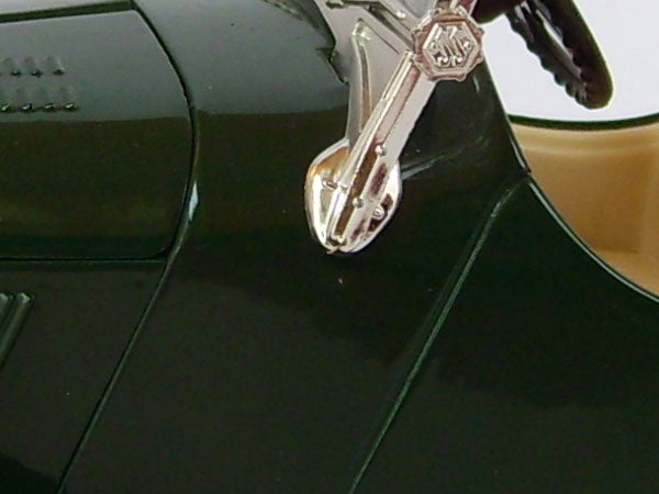 Close-up of a guitar-shaped key on a glossy surface.