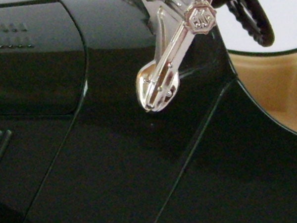 Close-up of a shiny zipper slider on a black surface.
