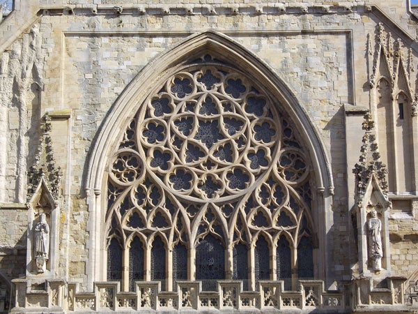 Ornate gothic window on historic stone cathedral facade.