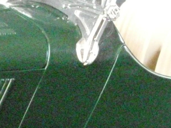 Close-up of guitar body and tuning pegs with blurred background.