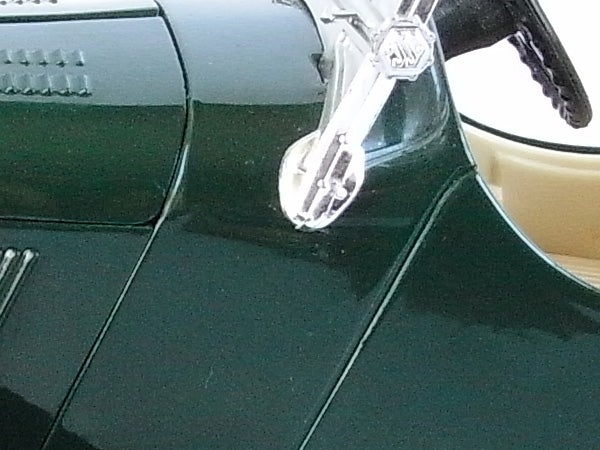 Close-up of a vintage car's shiny chrome handle and green bodywork.