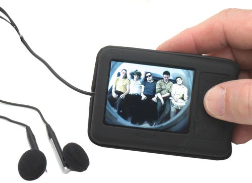 Hand holding Creative Zen 4GB MP3 player with earphones.