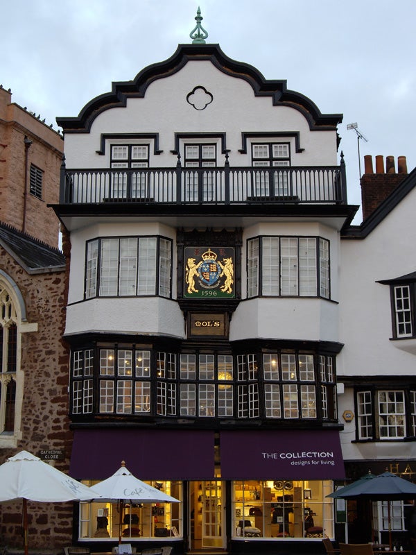 Historic building facade with ornate emblem and ground floor cafe