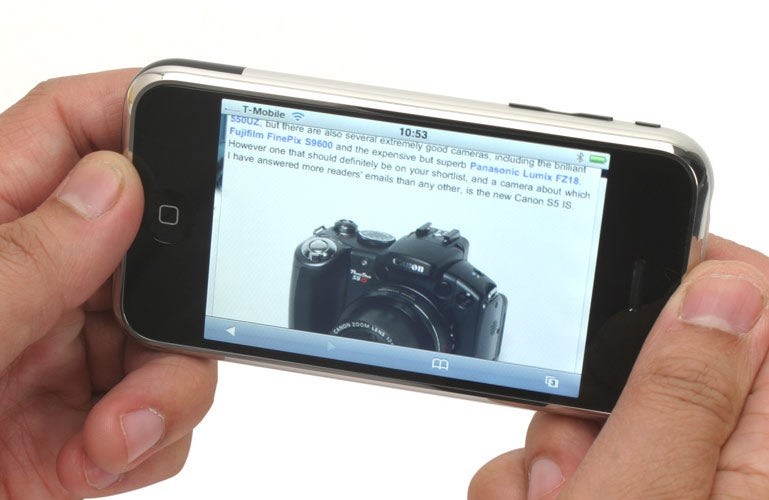 Hand holding an iPhone displaying a camera review article.