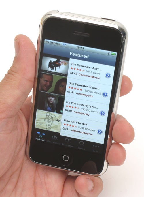 Hand holding an original iPhone displaying video app screen